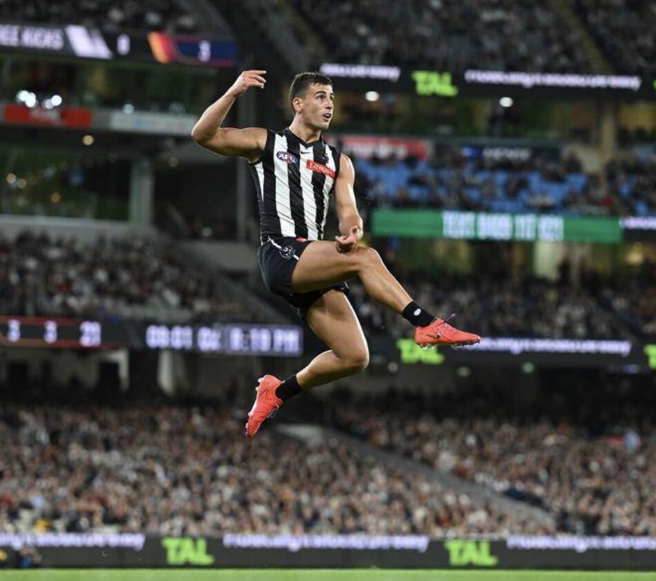 A Collingwood player sends a kick away under lights — the Magpies' season came down to one shot after the siren