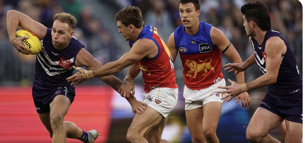 A Fremantle player breaks a Brisbane tackle — the Lions beat the Dockers by seven points in the 2026 Grand Final