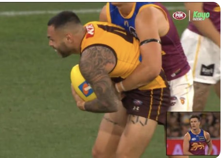A Hawthorn player is held in a tackle by a Brisbane opponent in the preliminary final — a holding-the-ball free kick with 36 seconds left decided the match